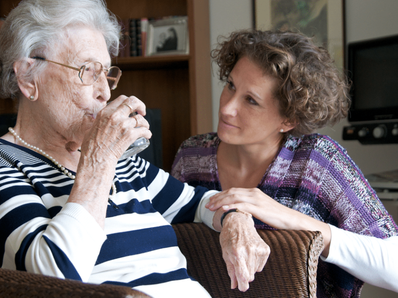 woman helping dehydrated senior